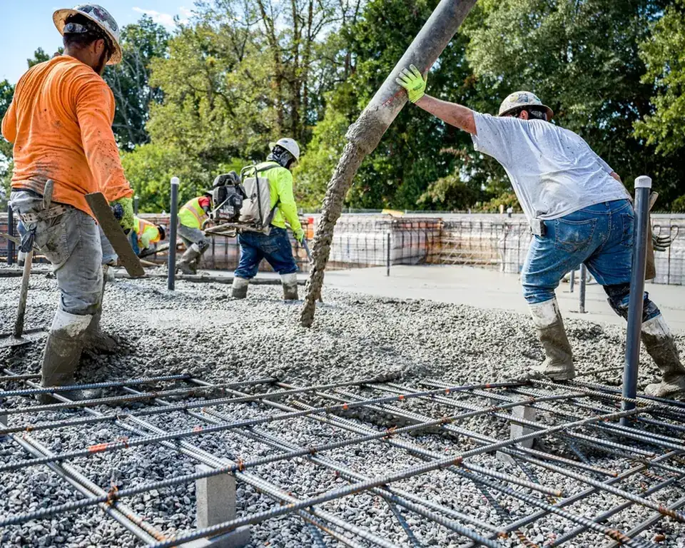 Workers pouring concrete over steel reinforcement on a building site