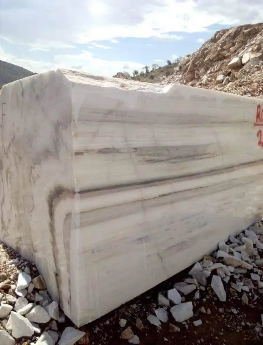 A large white marble block cut at the quarry