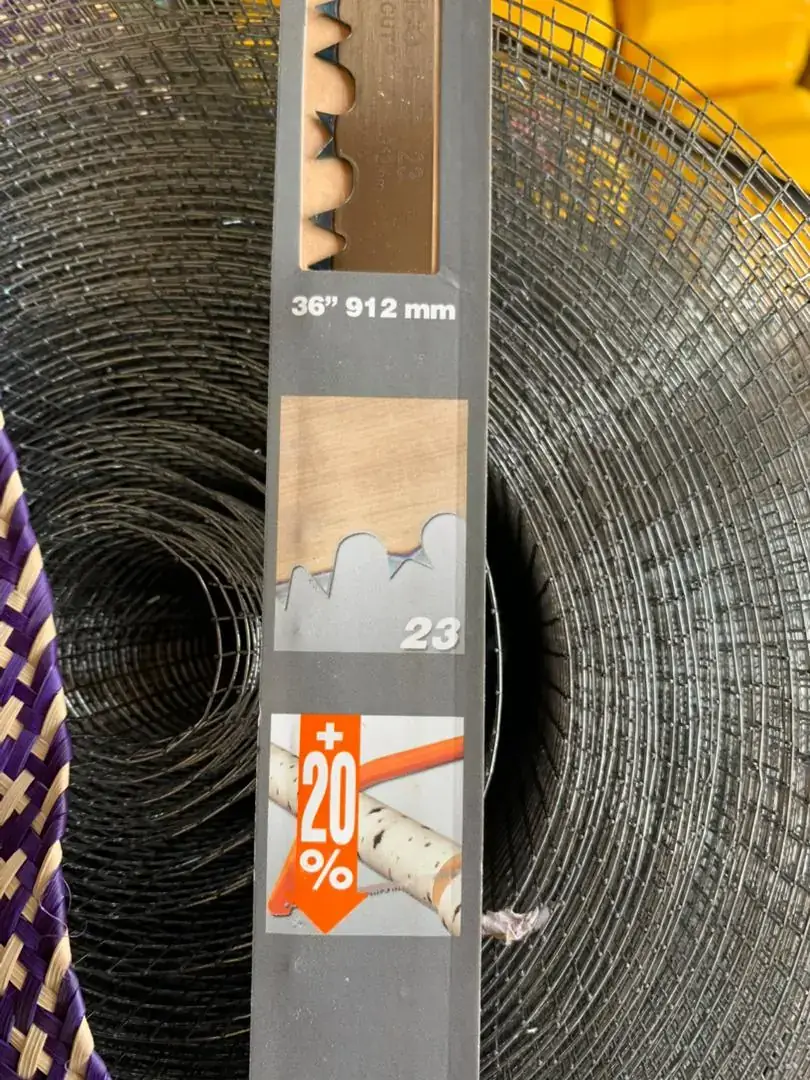A saw blade in its packaging in front of a roll of wire mesh